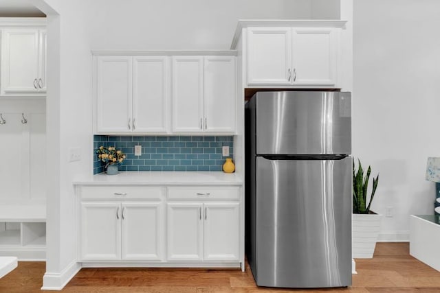 kitchen featuring decorative backsplash, light hardwood / wood-style flooring, white cabinets, and stainless steel fridge