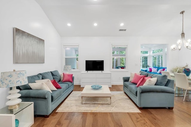 living room with vaulted ceiling, an inviting chandelier, and hardwood / wood-style floors