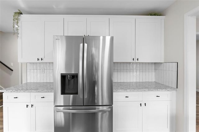 kitchen featuring backsplash, light stone counters, white cabinetry, and stainless steel refrigerator with ice dispenser