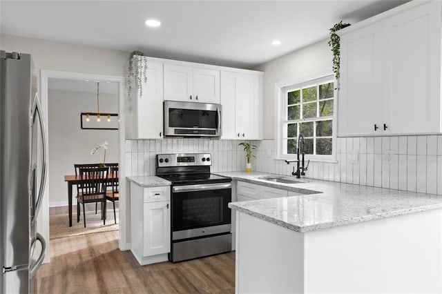 kitchen featuring light stone counters, stainless steel appliances, white cabinetry, and sink