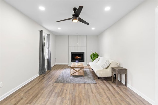 unfurnished living room featuring ceiling fan, a large fireplace, and light wood-type flooring