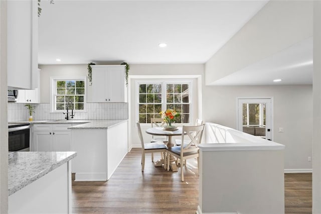 kitchen with tasteful backsplash, dark hardwood / wood-style flooring, white cabinets, and range