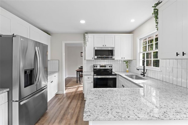 kitchen featuring white cabinets, stainless steel appliances, and light stone counters