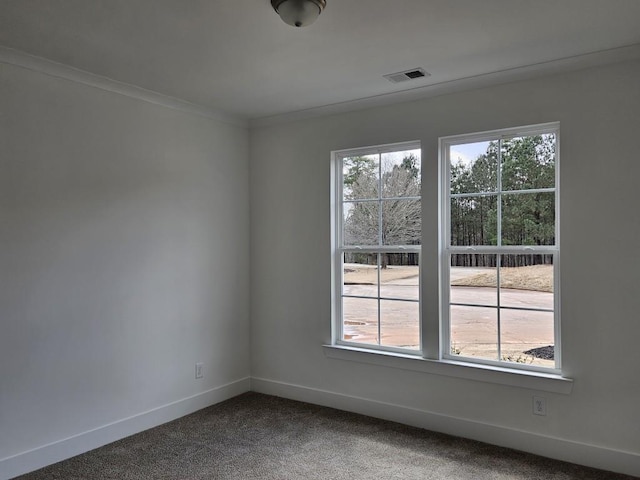 empty room with crown molding, carpet floors, visible vents, and baseboards