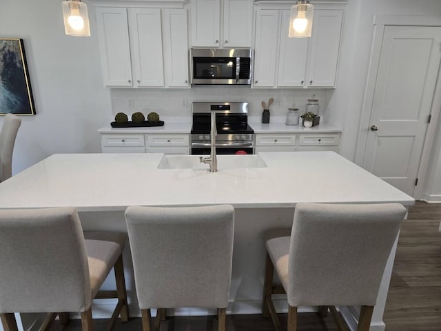 kitchen featuring a kitchen island with sink, a breakfast bar, pendant lighting, and appliances with stainless steel finishes