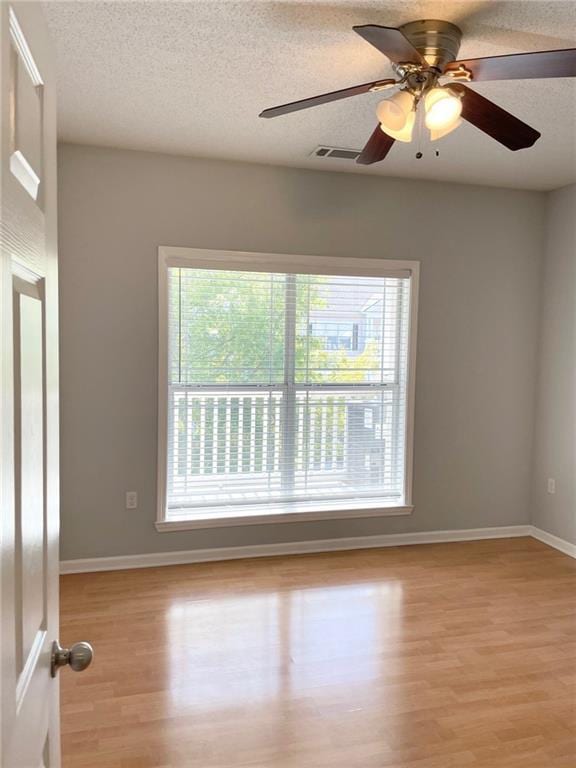 empty room featuring ceiling fan, a textured ceiling, and light hardwood / wood-style floors