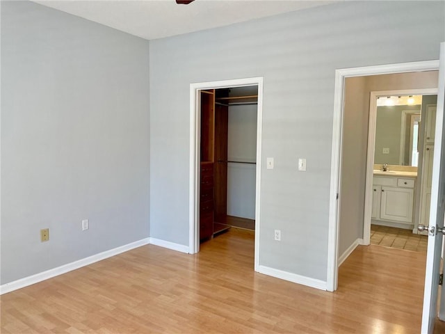 unfurnished bedroom with a closet, a walk in closet, and light hardwood / wood-style flooring