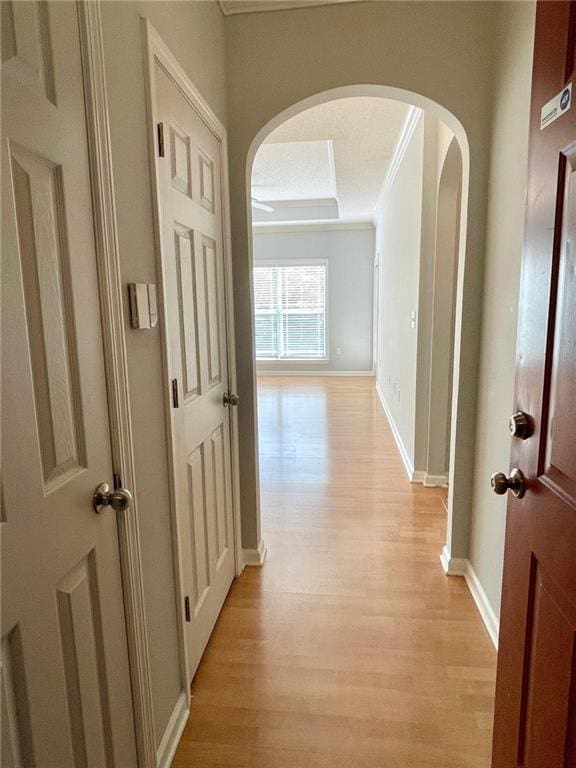 corridor with ornamental molding and light hardwood / wood-style floors