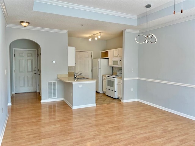 kitchen featuring pendant lighting, sink, white appliances, white cabinets, and kitchen peninsula