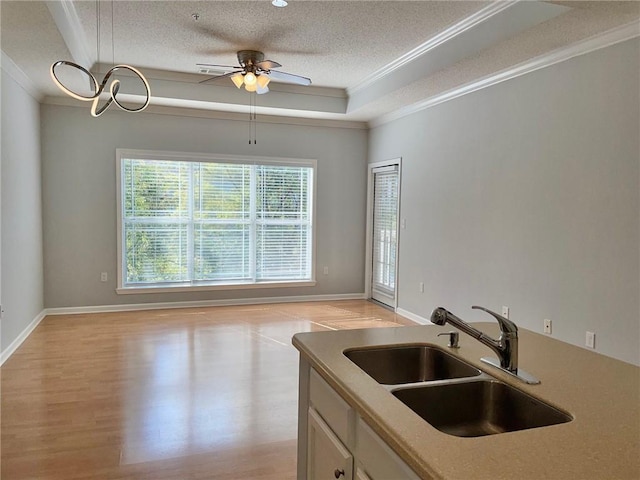 kitchen featuring crown molding, sink, a textured ceiling, and light hardwood / wood-style flooring