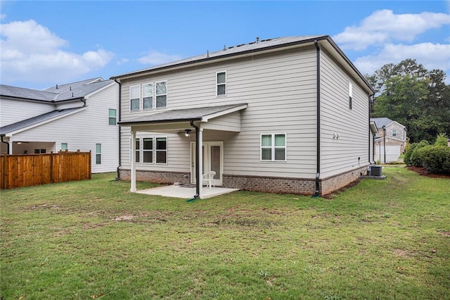 back of house featuring central air condition unit, a patio area, and a lawn