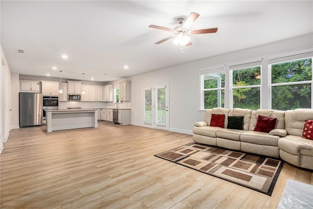 living room with light hardwood / wood-style flooring and ceiling fan