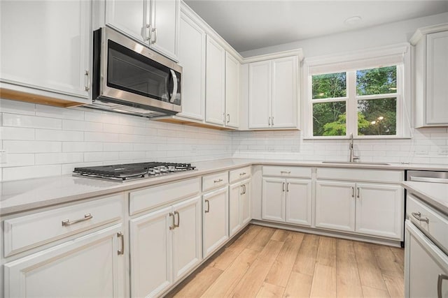 kitchen with light hardwood / wood-style floors, white cabinetry, stainless steel appliances, and sink