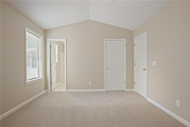 spare room featuring vaulted ceiling, light carpet, and a textured ceiling