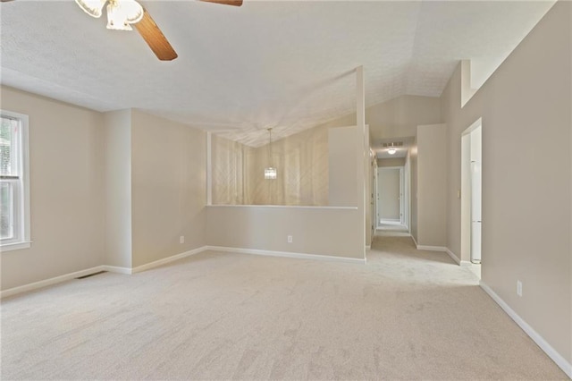 empty room featuring a textured ceiling, vaulted ceiling, ceiling fan, and carpet