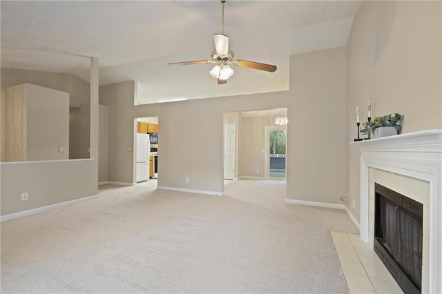 unfurnished living room featuring vaulted ceiling, ceiling fan, light carpet, and a tile fireplace