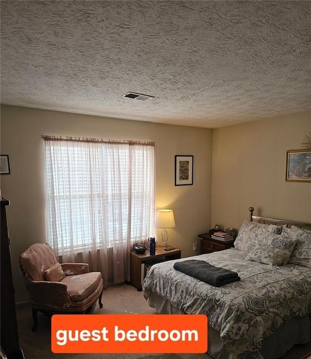 carpeted bedroom with a textured ceiling and visible vents