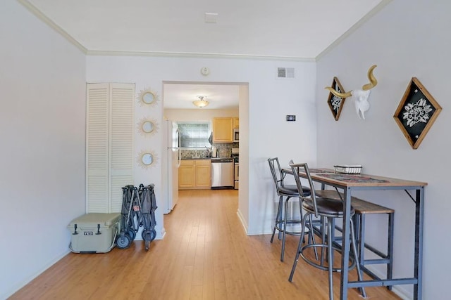 dining area featuring crown molding and light wood-type flooring