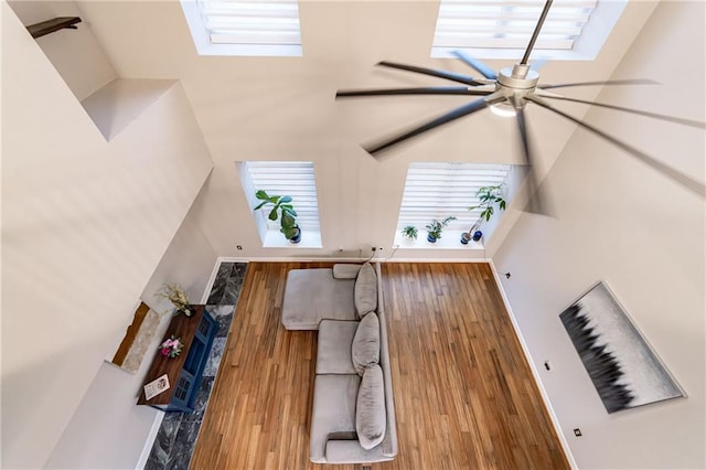 living room with a skylight, a towering ceiling, a healthy amount of sunlight, and hardwood / wood-style flooring