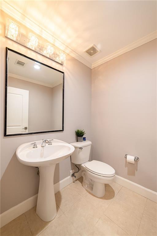 bathroom featuring tile patterned flooring, ornamental molding, and toilet