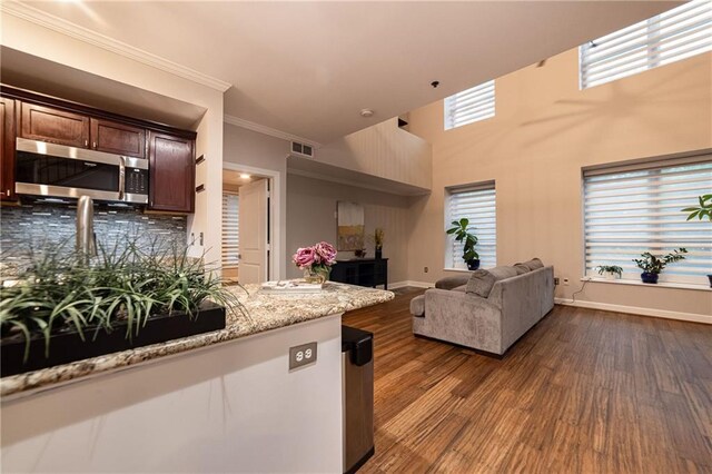 kitchen featuring decorative backsplash, a healthy amount of sunlight, dark hardwood / wood-style flooring, and ornamental molding