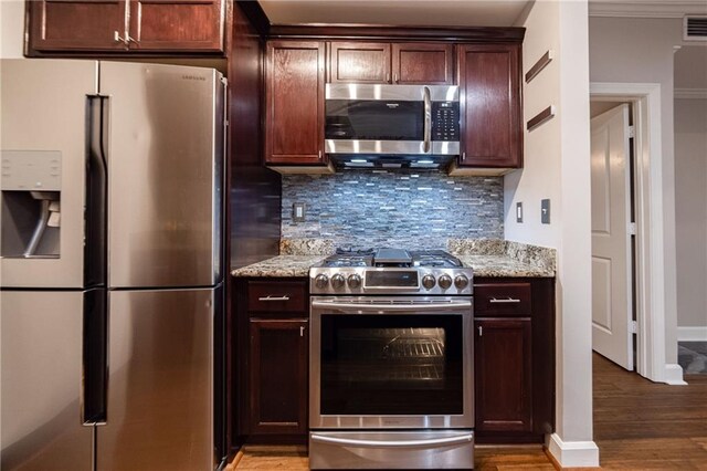 kitchen featuring light stone countertops, decorative backsplash, stainless steel appliances, crown molding, and hardwood / wood-style flooring