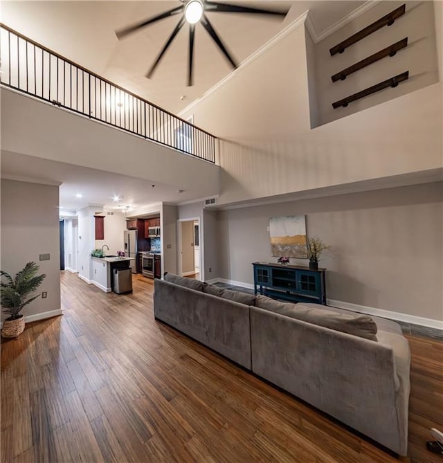 living room featuring a high ceiling, sink, crown molding, and wood-type flooring