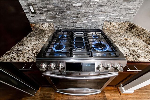 interior details with stone counters, wood-type flooring, and stainless steel stove