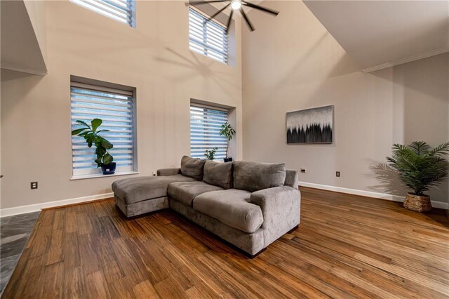 living room with a towering ceiling, hardwood / wood-style flooring, and ceiling fan