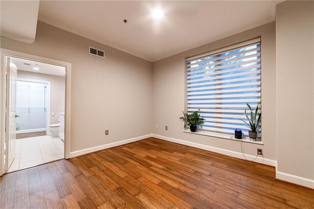 unfurnished room with hardwood / wood-style floors and crown molding