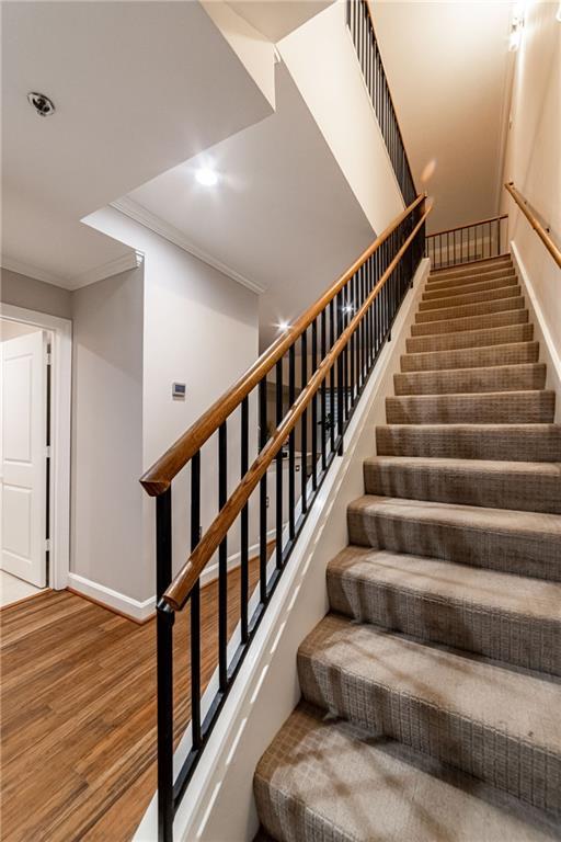 stairway with crown molding and hardwood / wood-style flooring