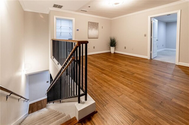 stairway with hardwood / wood-style floors and ornamental molding