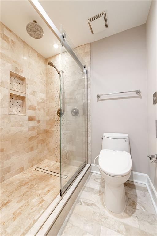 bathroom featuring a shower with shower door and toilet