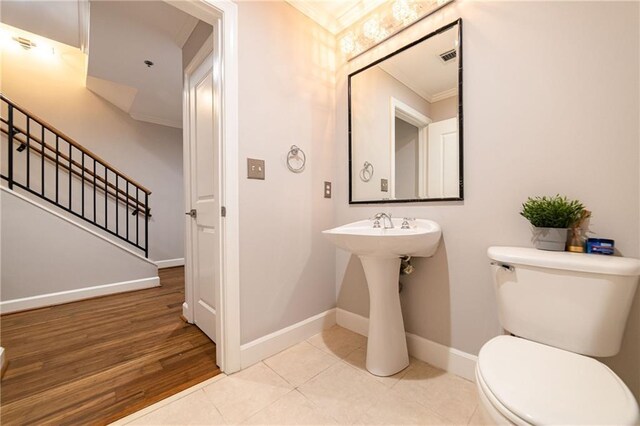 bathroom featuring hardwood / wood-style flooring, toilet, and ornamental molding