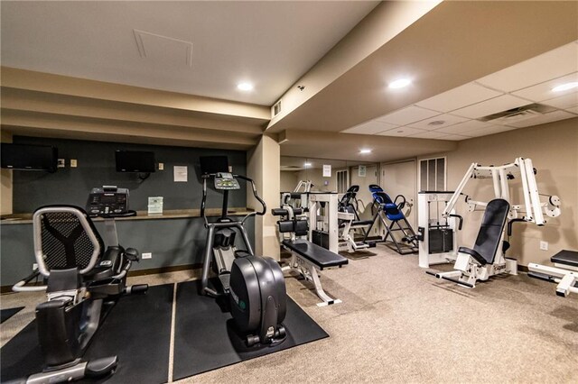 workout area featuring carpet and a drop ceiling