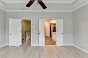 1668 Sabastian Pt NE, Atlanta, GA 30329 - unfurnished bedroom with baseboards, a tray ceiling, ornamental molding, and wood finished floors