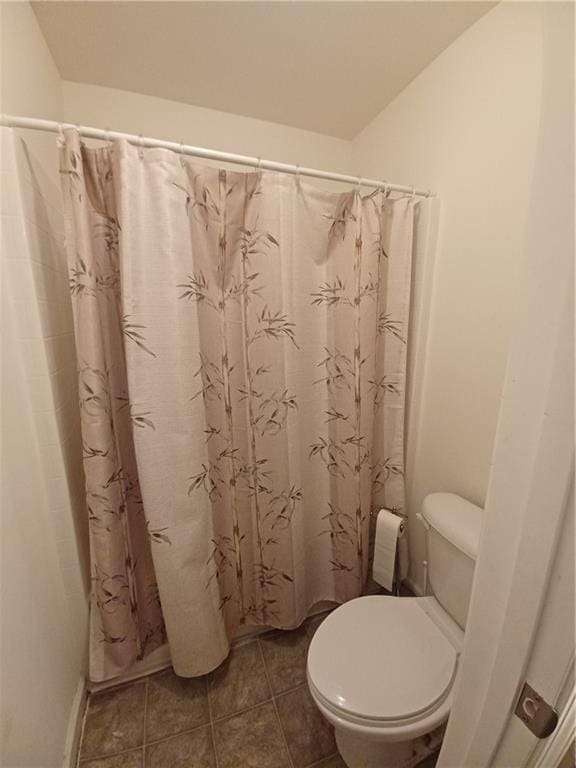 bathroom featuring toilet, a shower with curtain, and tile patterned floors