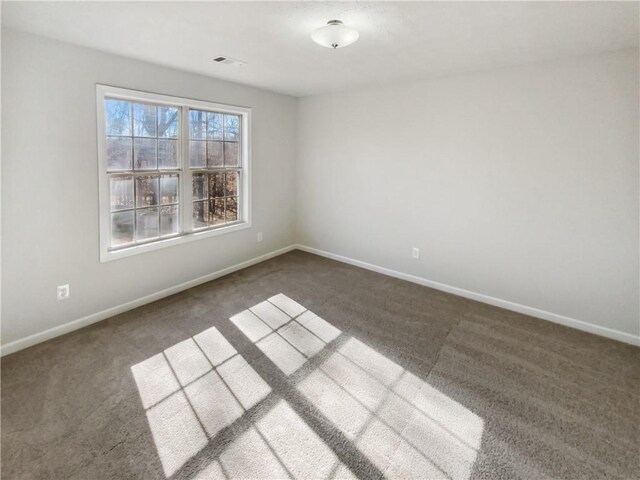 spare room with carpet flooring, visible vents, and baseboards