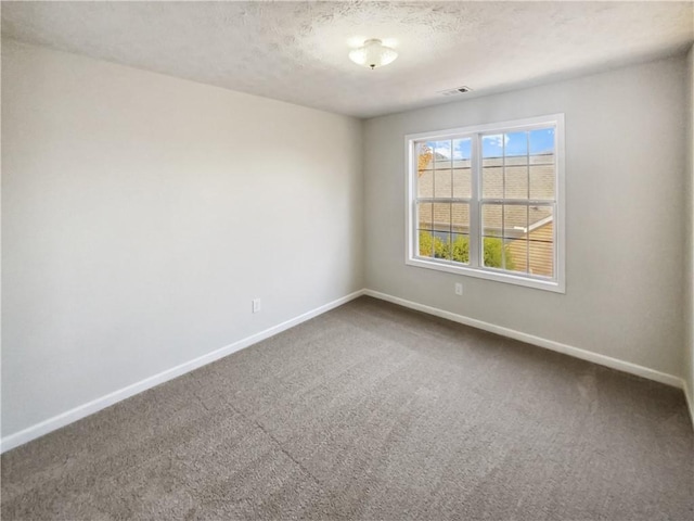 carpeted empty room with visible vents, baseboards, and a textured ceiling