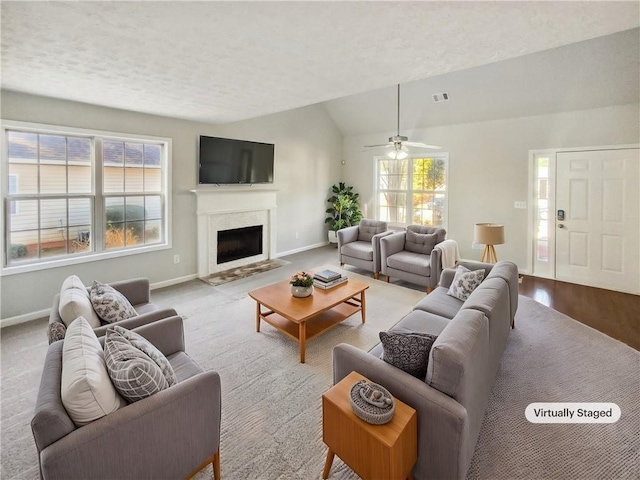 living area with baseboards, visible vents, vaulted ceiling, a textured ceiling, and a fireplace