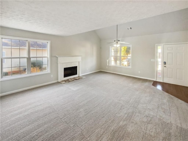 unfurnished living room with lofted ceiling, baseboards, a textured ceiling, and carpet flooring