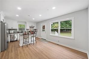 440 Colbert Rd, Dallas, GA 30132 - kitchen with stainless steel appliances, a breakfast bar area, white cabinets, recessed lighting, and wood finished floors
