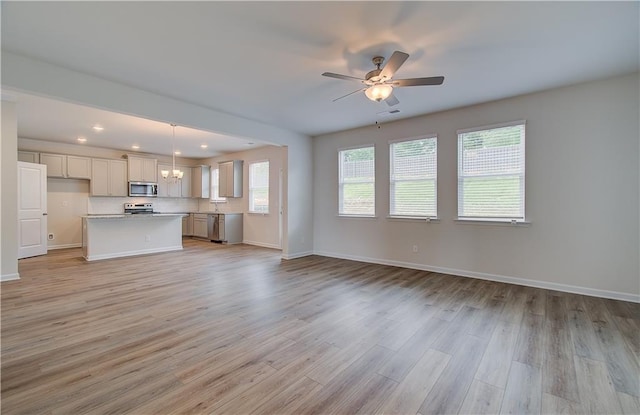 1054 Georgian Point Dr, Lawrenceville, GA 30045 - unfurnished living room with baseboards, light wood-type flooring, recessed lighting, and ceiling fan with notable chandelier