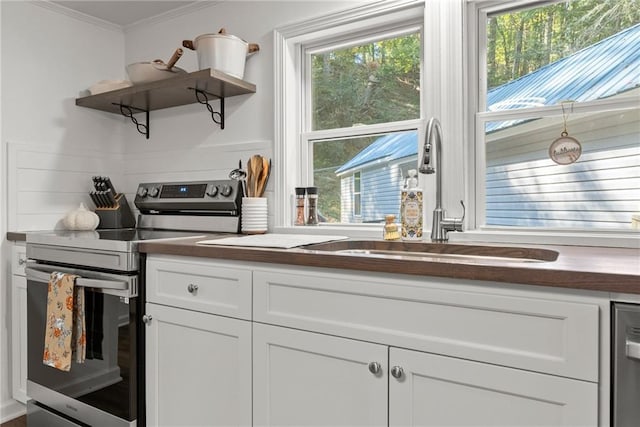 kitchen with a healthy amount of sunlight, ornamental molding, open shelves, and stainless steel range with electric cooktop