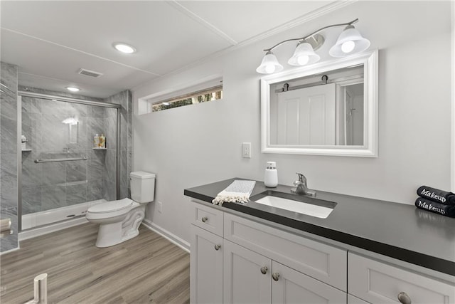 bathroom with visible vents, toilet, wood finished floors, vanity, and a shower stall