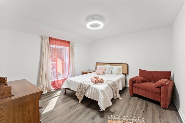 bedroom with lofted ceiling and light wood finished floors