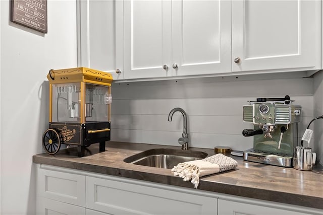 kitchen featuring dark countertops, white cabinetry, and a sink