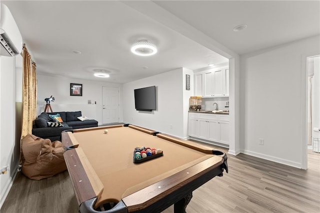 rec room featuring light wood-style flooring, an AC wall unit, a sink, billiards, and baseboards