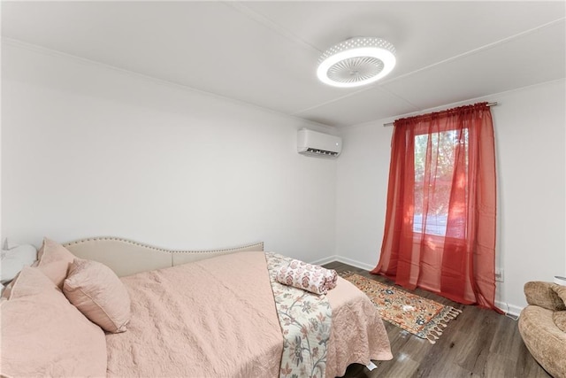 bedroom with a wall mounted AC, wood finished floors, and baseboards