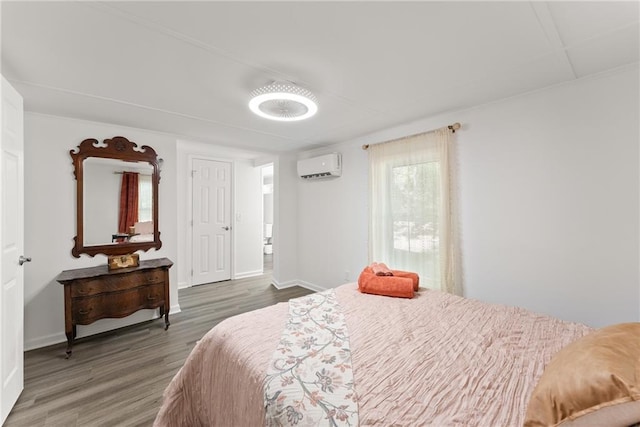 bedroom with baseboards, an AC wall unit, and wood finished floors